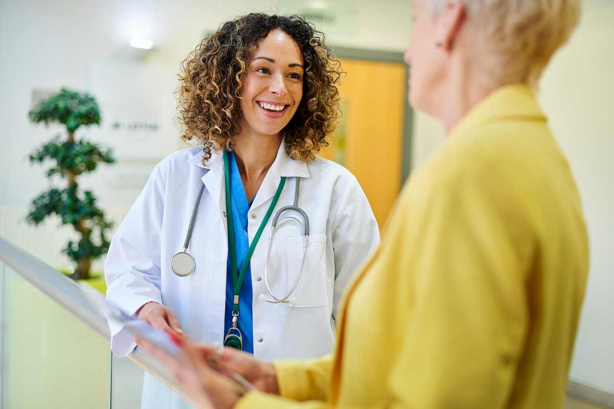 Female doctor smiles at woman holding clipboard